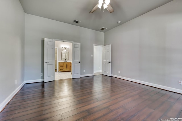 unfurnished bedroom featuring a high ceiling, ensuite bathroom, dark hardwood / wood-style floors, and ceiling fan