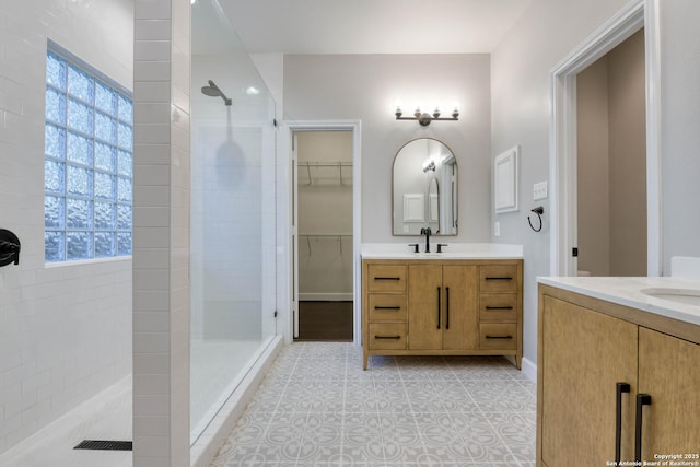 bathroom featuring tiled shower, vanity, and tile patterned flooring