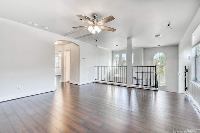 spare room with dark wood-type flooring and ceiling fan with notable chandelier