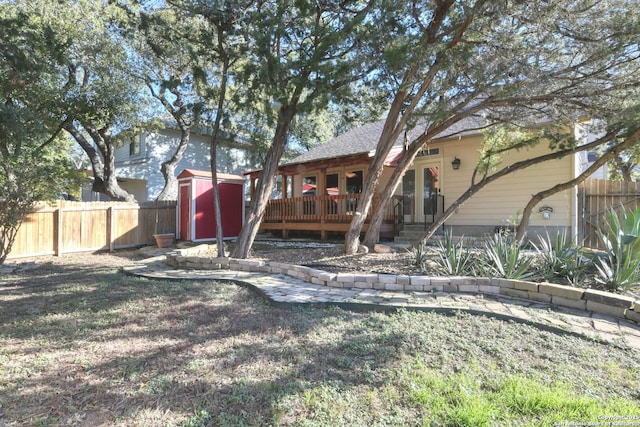 rear view of property featuring a lawn, a deck, and a storage shed