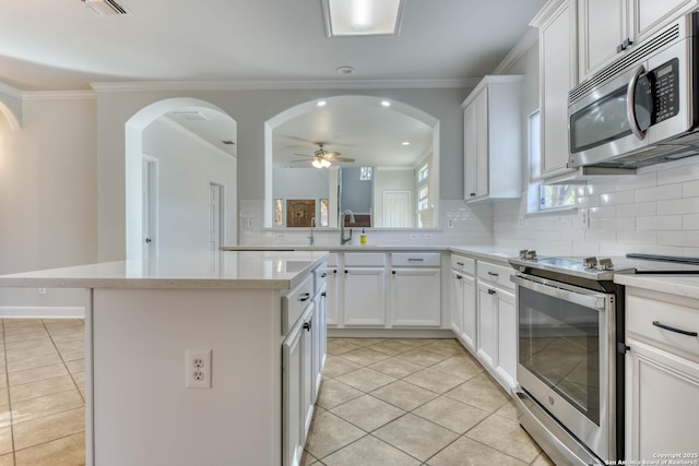 kitchen featuring a kitchen island, white cabinets, light tile patterned floors, ceiling fan, and stainless steel appliances