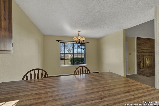 unfurnished dining area with a textured ceiling, an inviting chandelier, and a fireplace