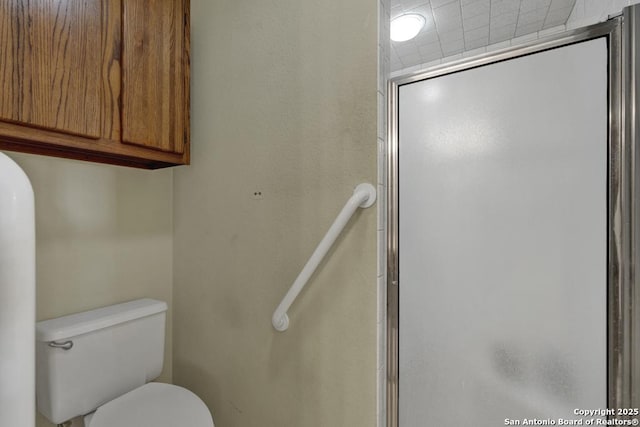 bathroom with a shower with door and toilet