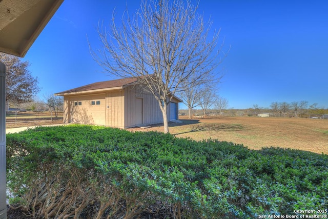 view of yard featuring a rural view, a garage, and an outdoor structure