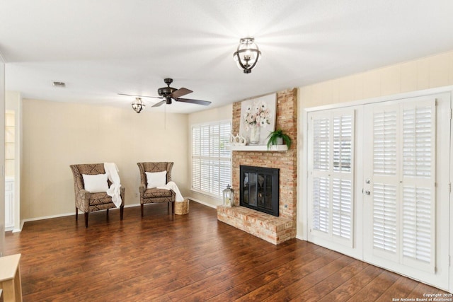 sitting room featuring a brick fireplace, ceiling fan, and dark hardwood / wood-style floors