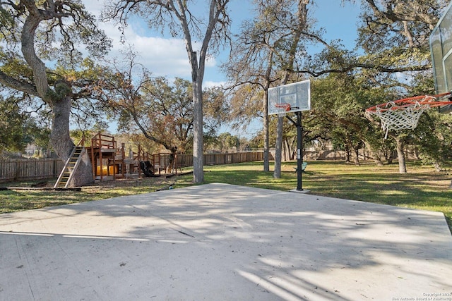 view of basketball court featuring a playground and a lawn