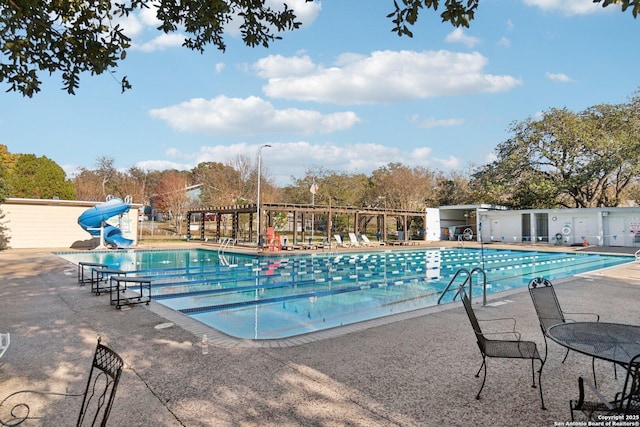 view of pool with a water slide and a patio