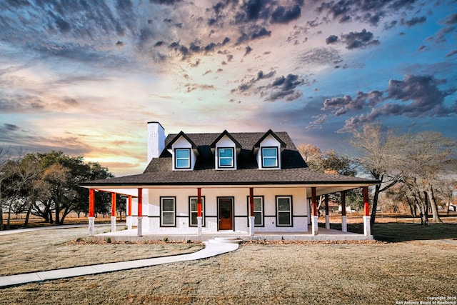 country-style home with covered porch and a yard