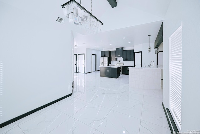 interior space featuring stainless steel stove, a chandelier, hanging light fixtures, a center island, and fridge with ice dispenser