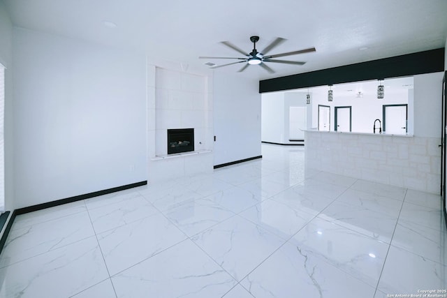 unfurnished living room featuring a large fireplace and ceiling fan