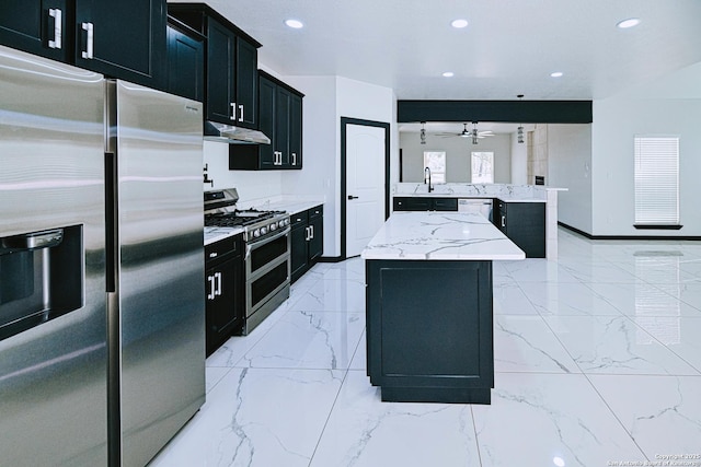 kitchen featuring stainless steel appliances, sink, light stone counters, ceiling fan, and a kitchen island