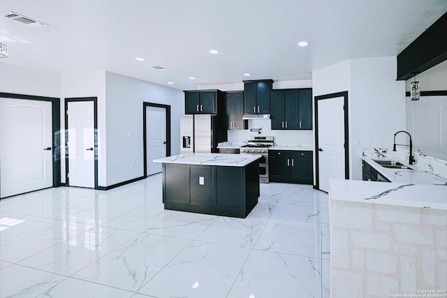 kitchen with kitchen peninsula, stainless steel appliances, light stone countertops, and sink