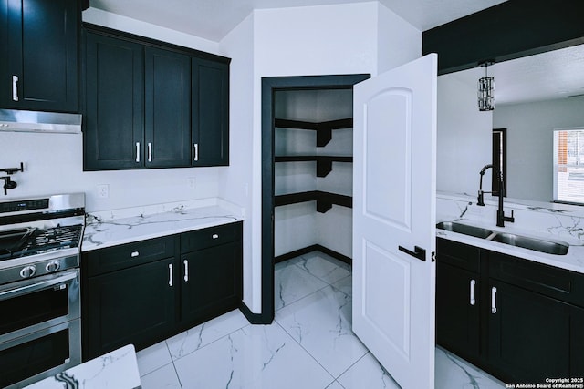 kitchen featuring light stone counters, extractor fan, range with two ovens, pendant lighting, and sink