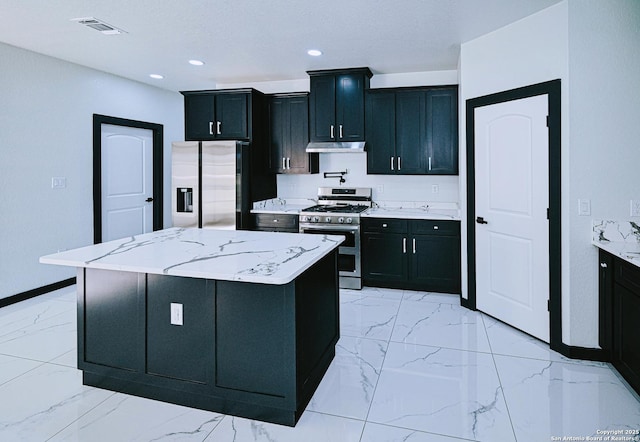 kitchen featuring stainless steel appliances, a kitchen island, and light stone countertops