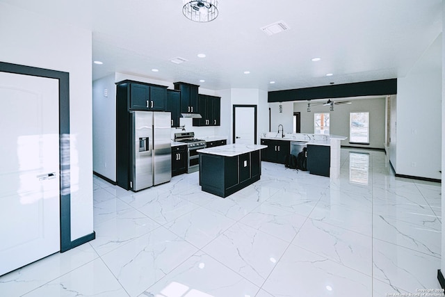 kitchen with kitchen peninsula, a center island, appliances with stainless steel finishes, ceiling fan, and sink