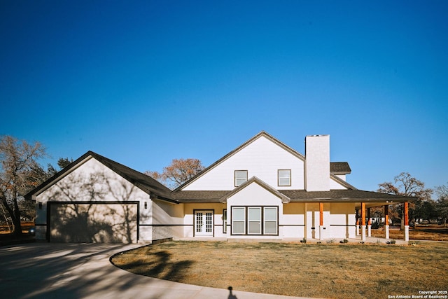 back of property featuring covered porch, a yard, and a garage