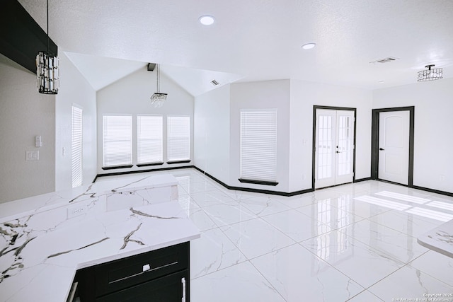 unfurnished living room featuring lofted ceiling and french doors