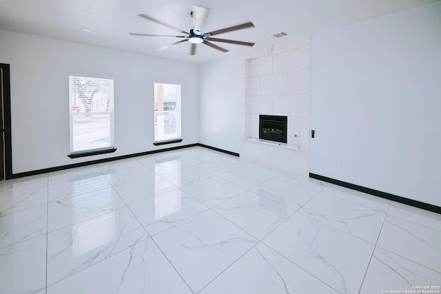 spare room with a tile fireplace, ceiling fan, and heating unit