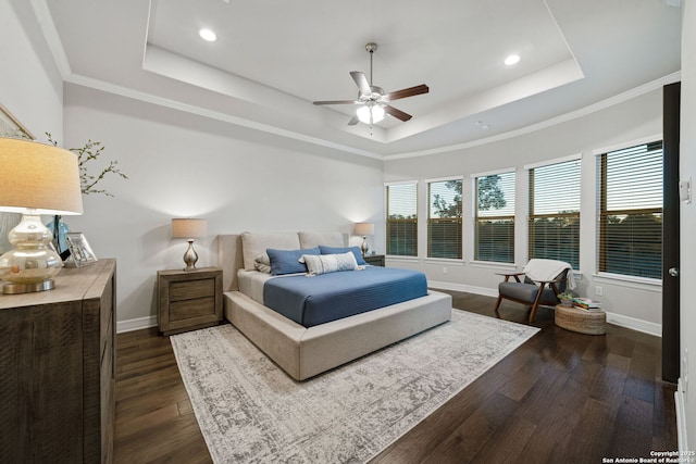 bedroom with dark wood-type flooring, a raised ceiling, ceiling fan, and ornamental molding