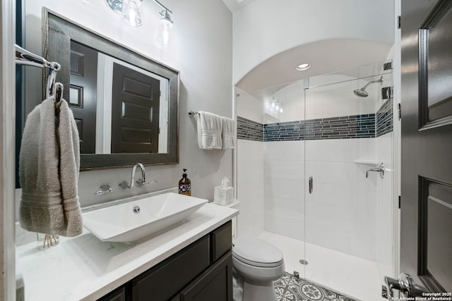 bathroom with toilet, a shower with door, and vanity