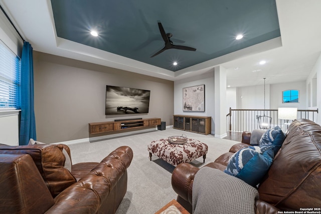 carpeted living room featuring ceiling fan and a tray ceiling