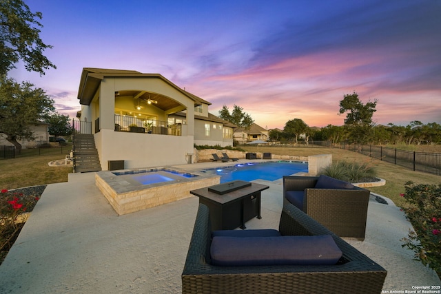 pool at dusk with a patio area and an in ground hot tub