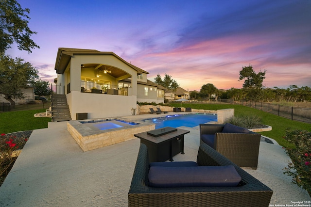 pool at dusk with a patio, an in ground hot tub, and a yard