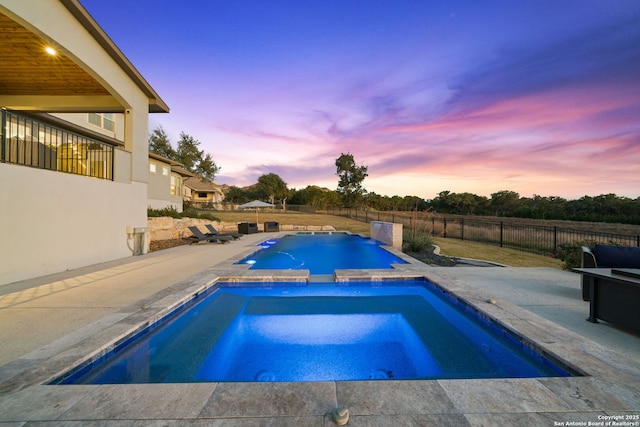 pool at dusk featuring an in ground hot tub and a patio area