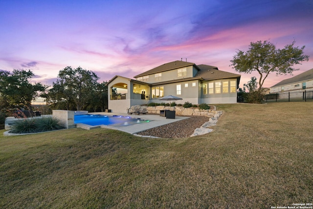 back house at dusk featuring a patio area, a lawn, and a fenced in pool