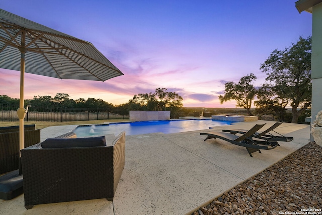 pool at dusk with pool water feature and a patio