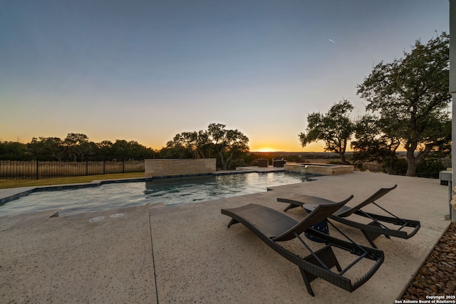 pool at dusk with a patio area