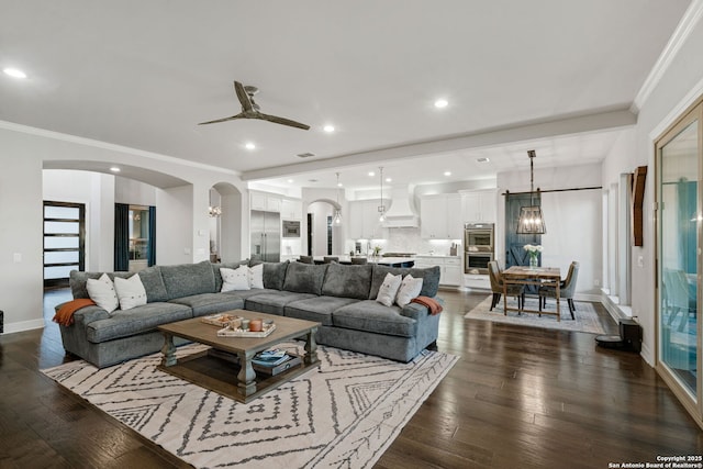 living room with ornamental molding, dark hardwood / wood-style floors, and ceiling fan with notable chandelier