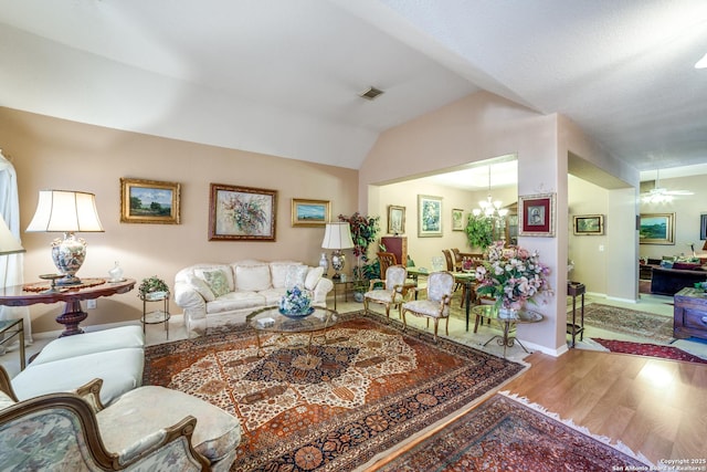 living room featuring ceiling fan with notable chandelier, vaulted ceiling, and hardwood / wood-style floors