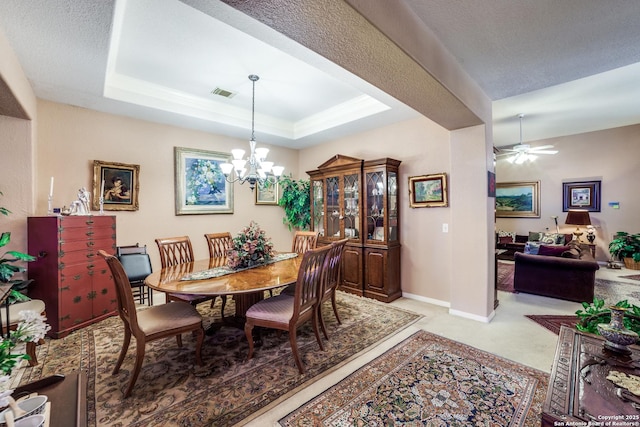 dining room featuring ceiling fan with notable chandelier and a tray ceiling