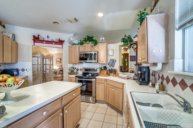 kitchen featuring appliances with stainless steel finishes, decorative backsplash, sink, and light tile patterned floors