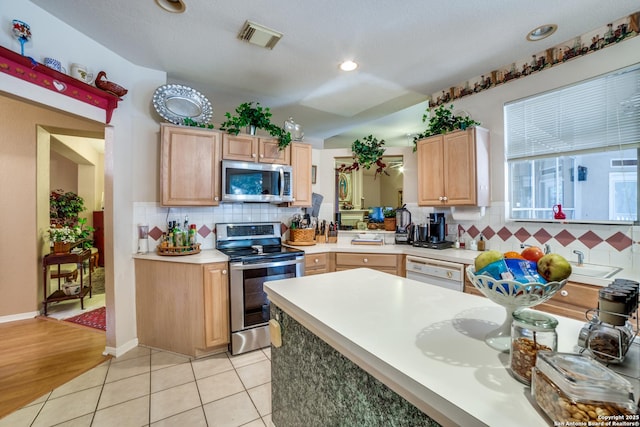 kitchen with stainless steel appliances, backsplash, light tile patterned flooring, and light brown cabinets