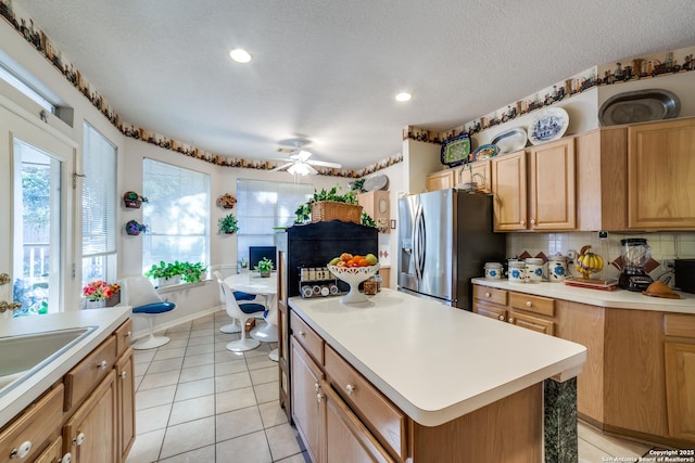 kitchen featuring a textured ceiling, a center island, decorative backsplash, and stainless steel refrigerator with ice dispenser