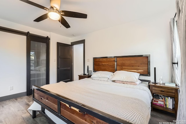 bedroom with ceiling fan, hardwood / wood-style floors, and a barn door