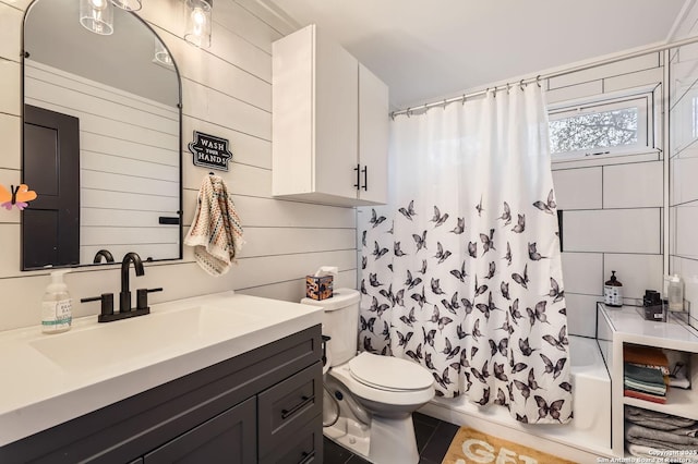 full bathroom with toilet, wooden walls, tile patterned floors, shower / tub combo, and vanity