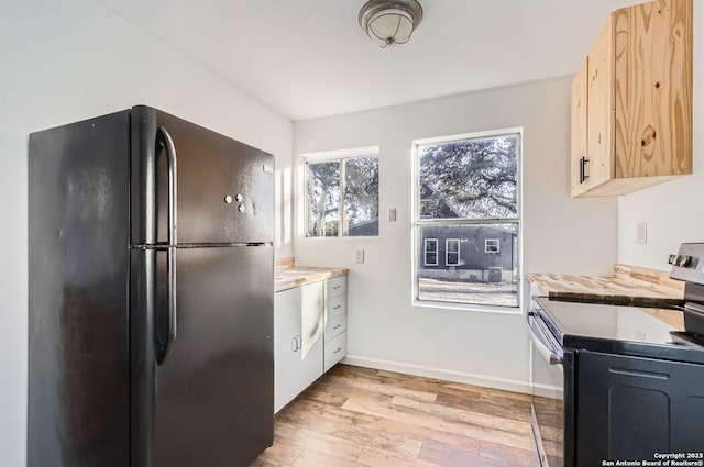 kitchen with a healthy amount of sunlight, stainless steel electric range, black refrigerator, and light brown cabinets