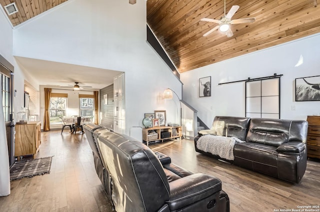 living room with hardwood / wood-style flooring, high vaulted ceiling, a barn door, and wooden ceiling