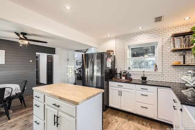 kitchen featuring ceiling fan, stainless steel fridge, wood counters, and white cabinetry