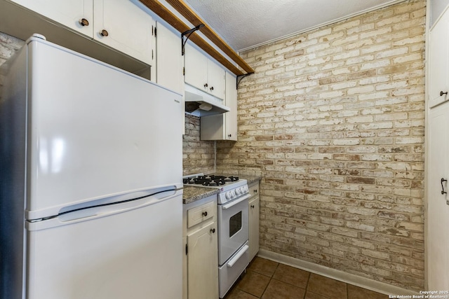 kitchen featuring brick wall, white appliances, and white cabinetry