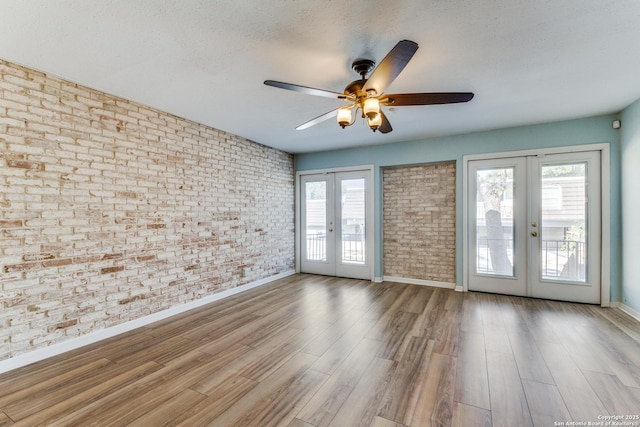 unfurnished room featuring brick wall, a textured ceiling, ceiling fan, and french doors