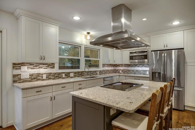 kitchen with a breakfast bar, sink, a center island, island exhaust hood, and stainless steel appliances