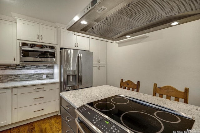 kitchen with dark hardwood / wood-style flooring, wall chimney range hood, stainless steel appliances, and light stone countertops