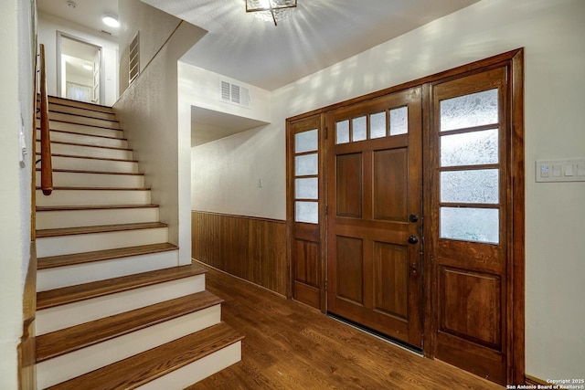 foyer entrance with dark hardwood / wood-style flooring and wood walls