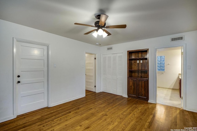 unfurnished bedroom featuring ensuite bath, ceiling fan, and light wood-type flooring