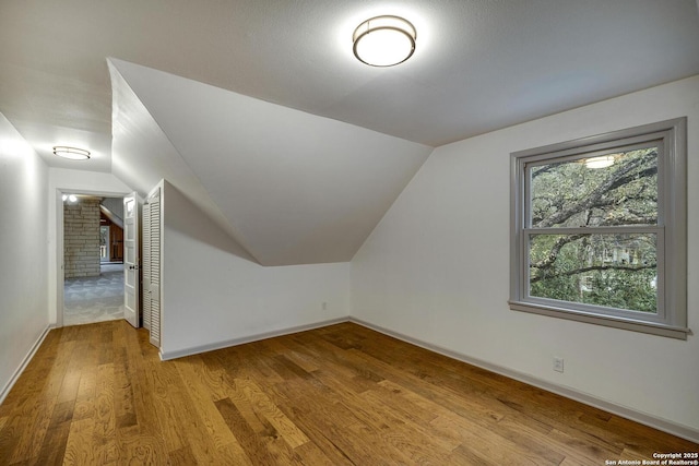 additional living space featuring lofted ceiling and light hardwood / wood-style floors