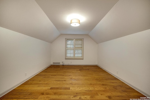 additional living space featuring lofted ceiling and light wood-type flooring